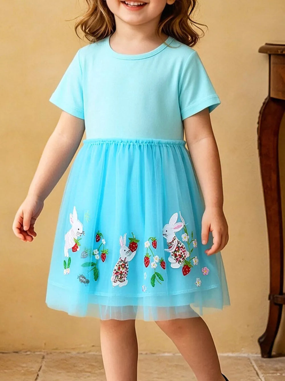 Baby blue cotton blend dress with embroidered bunnies and strawberries on a blue tulle skirt.