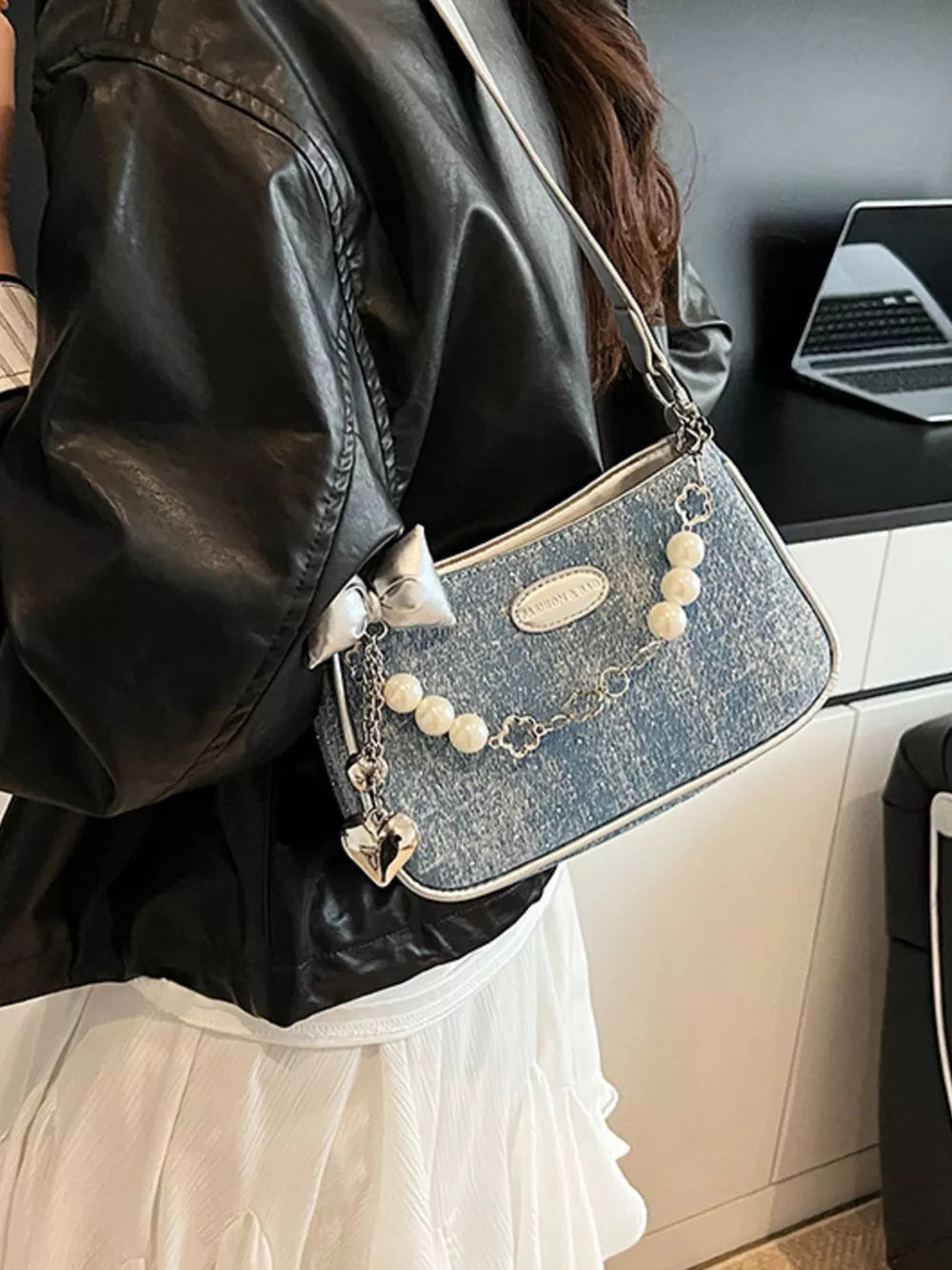Denim shoulder bag with pearl chain, heart charm, and bow detail.