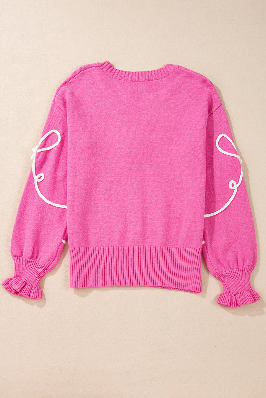 Fuchsia pink knit sweater with white embroidered bow motif on sleeves and ruffled cuffs.