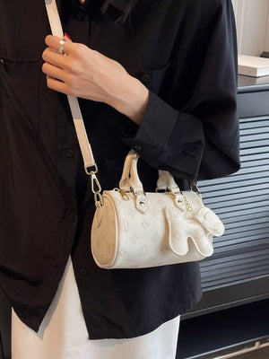 White mini barrel crossbody bag with embossed pattern and glove charm