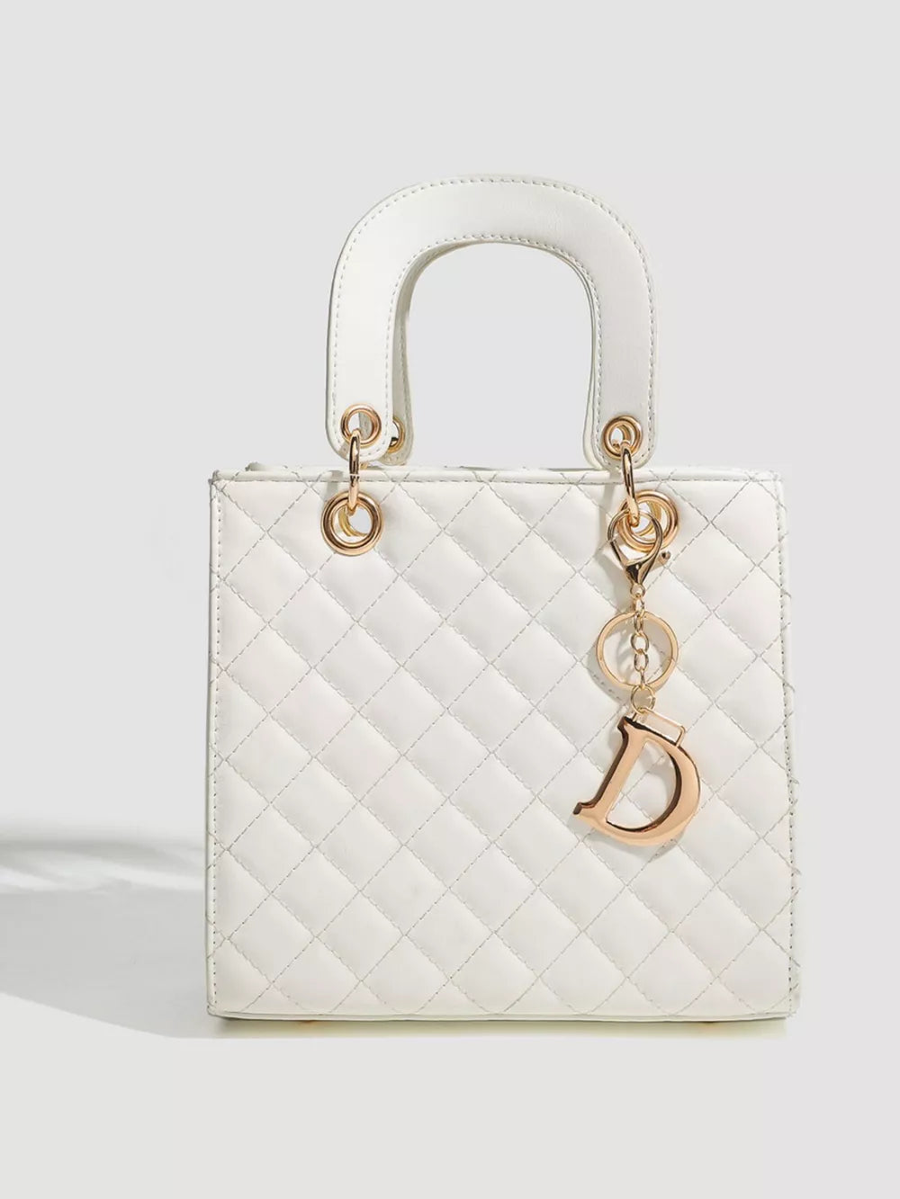 White quilted mini top-handle tote bag with gold D charm and top handle.