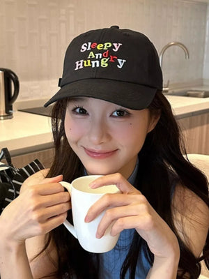 Black baseball cap with "Sleepy And Hungry" embroidery in colorful text