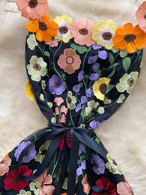 Black mini dress with colorful floral embroidery and a bow detail.