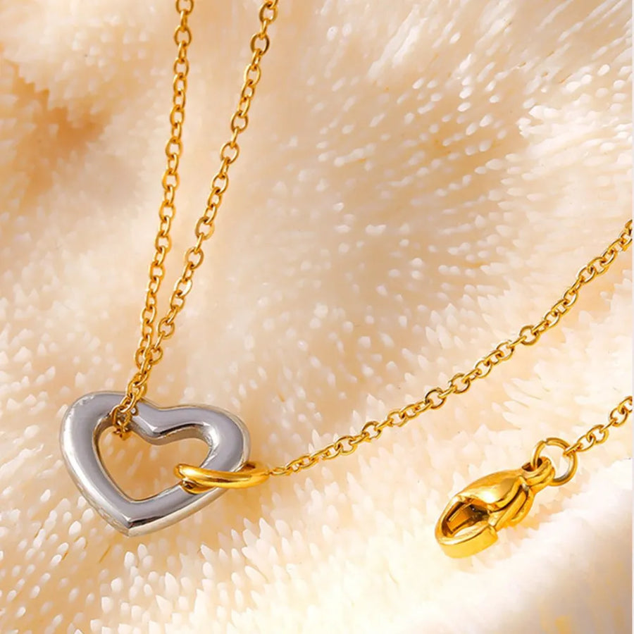Gold chain bracelet with a two-tone heart charm and lobster clasp.