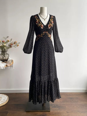 Black polka dot maxi dress with embroidered floral detail and ruffled hem.