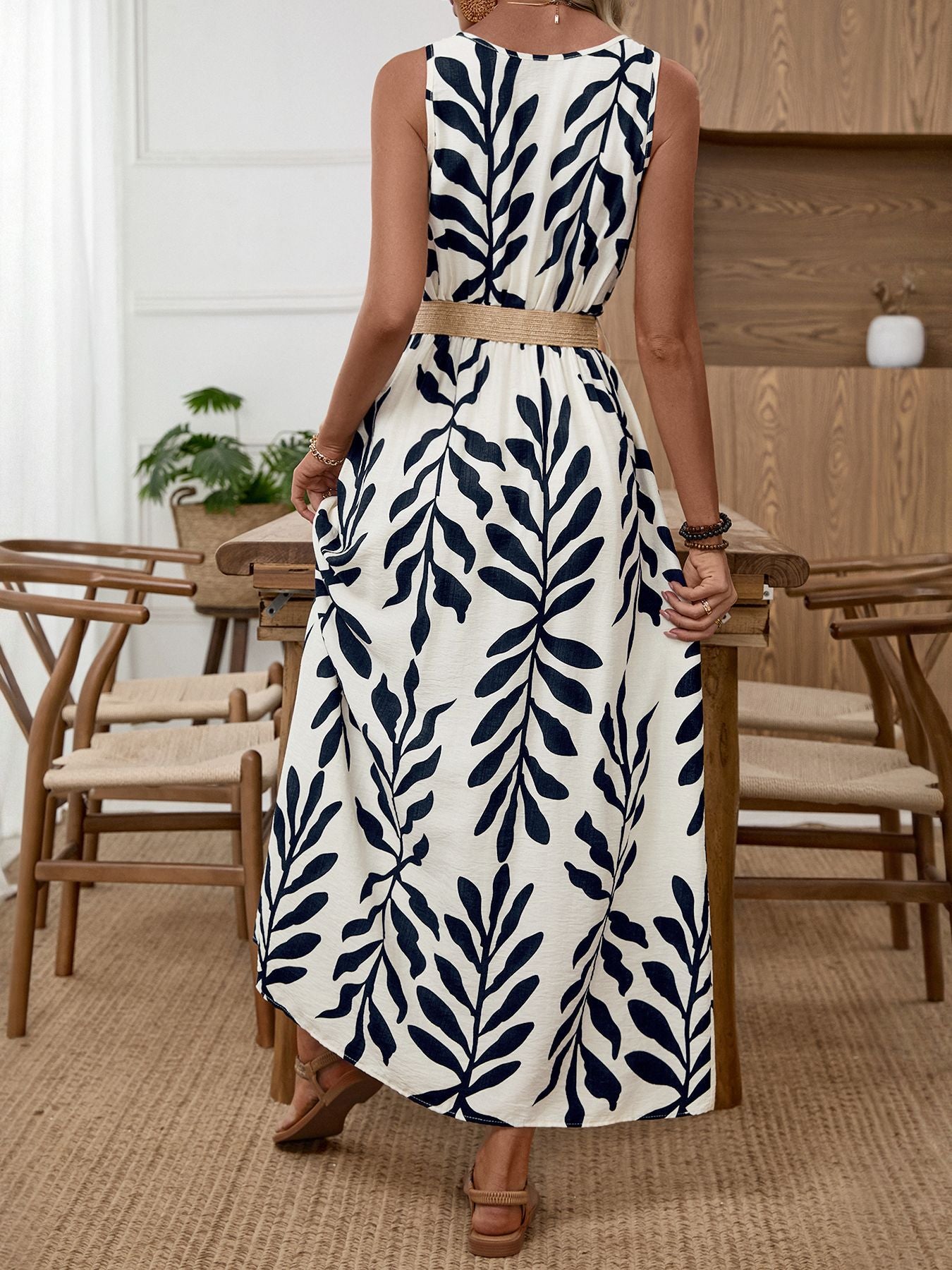 Belted midi dress with a tropical leaf print, natural fiber belt, and sleeveless design.