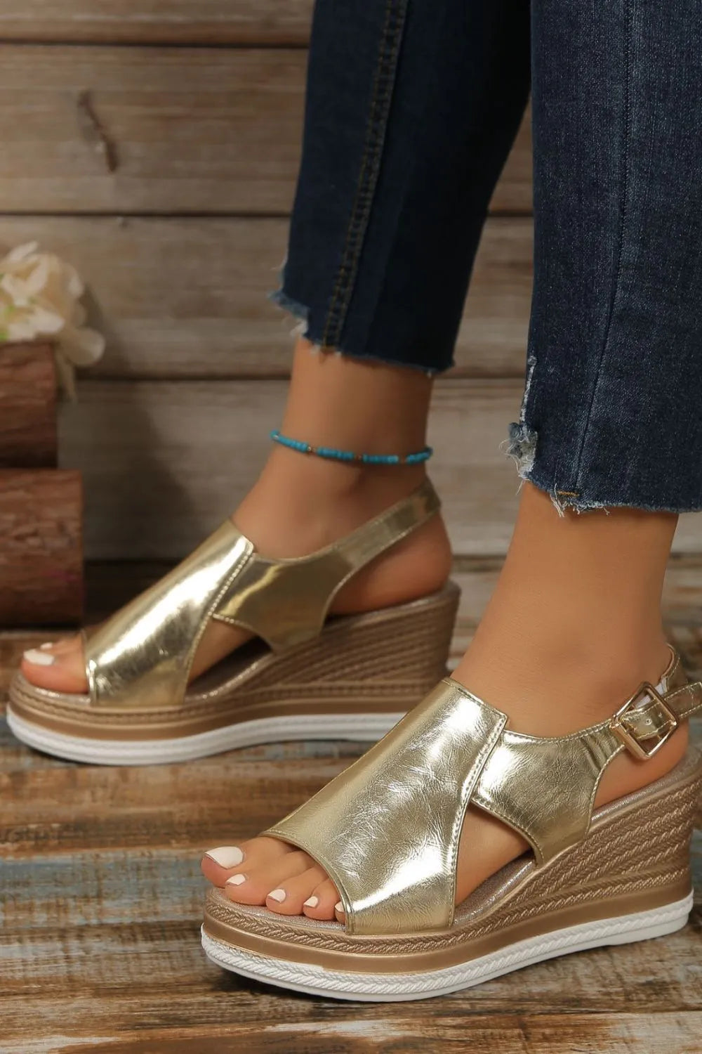 Gold metallic wedge sandals with crisscross detail and buckle ankle strap.