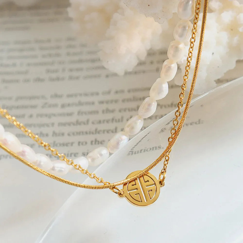 Gold layered bracelet with pearls, chain, and a circular charm.