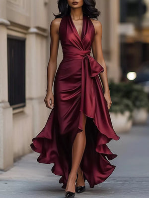 Burgundy halter maxi dress with ruffled asymmetrical hem and tie waist detail.