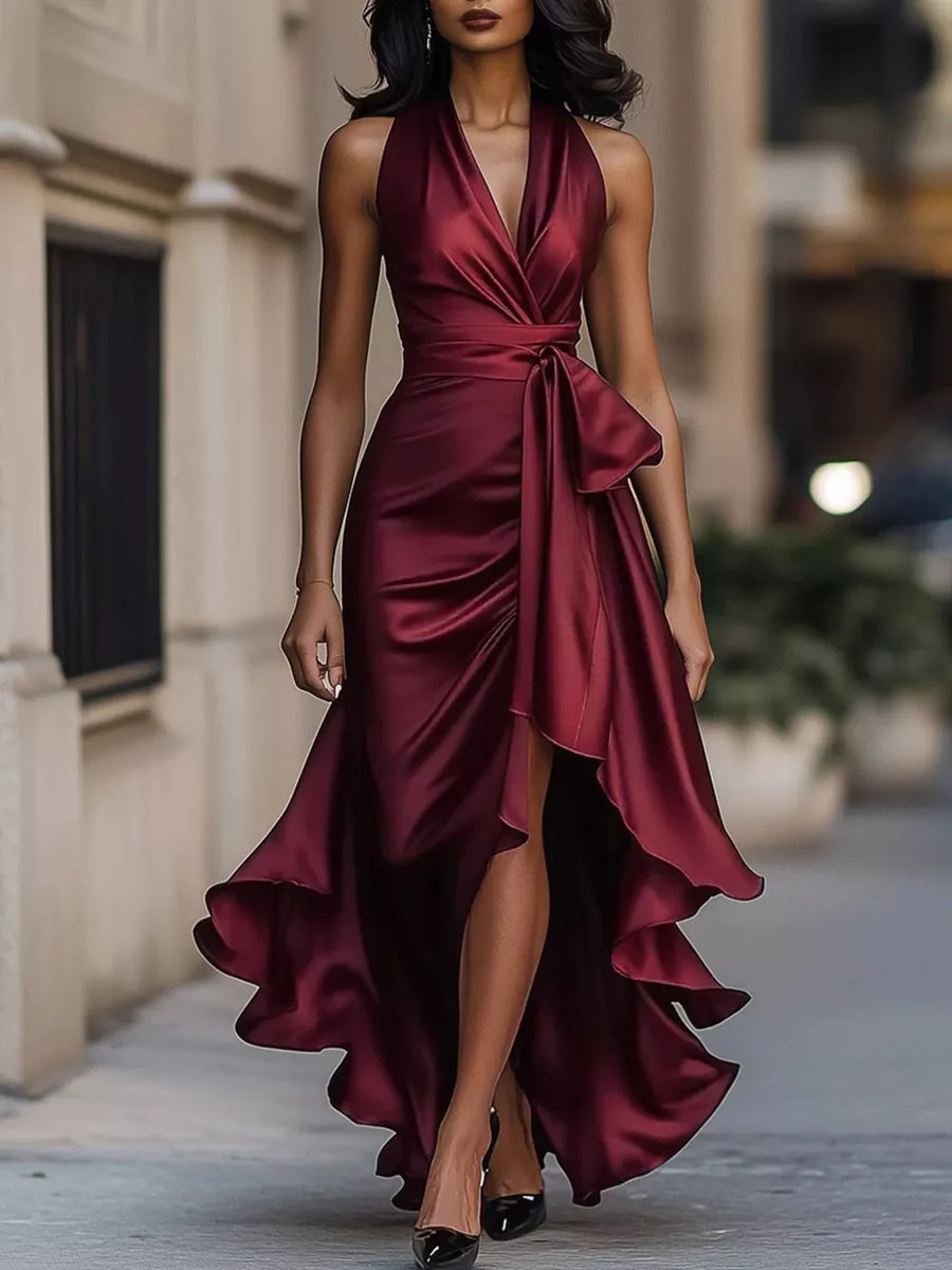 Burgundy halter maxi dress with ruffled asymmetrical hem and tie waist detail.