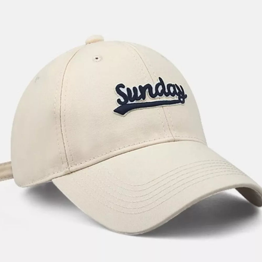 Cream baseball cap with navy blue embroidered Sunday text and adjustable strap