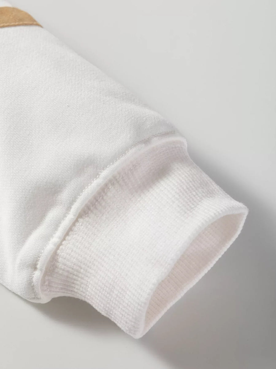 White knit loungewear top sleeve with ribbed cuff detail and tan accent.