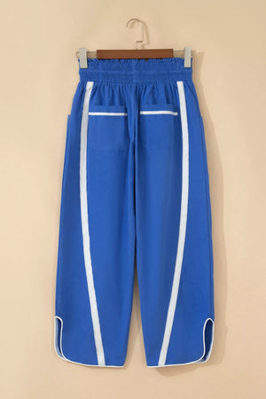 Blue smocked waist cropped casual pants with white side stripes and pocket trim.