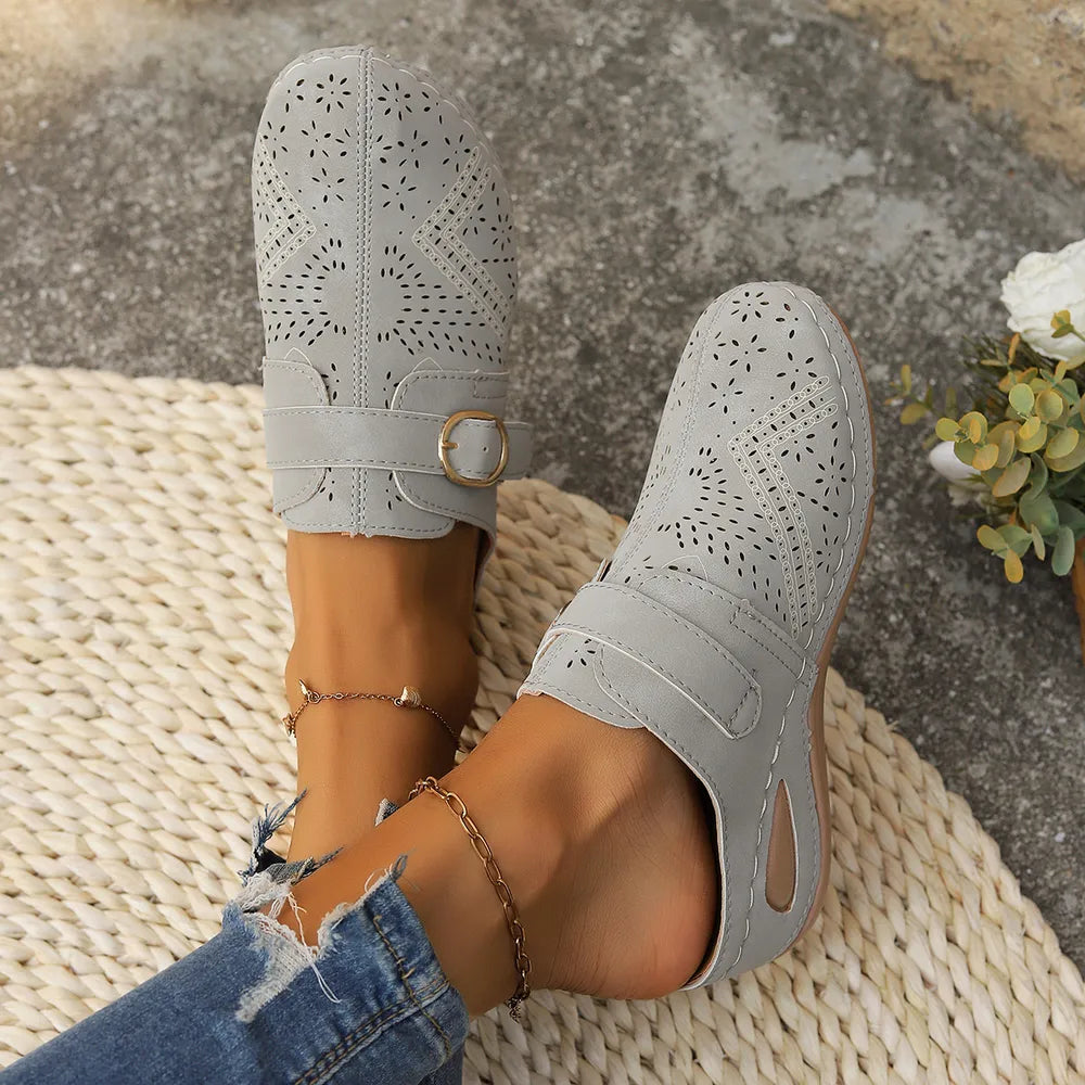 Gray laser-cut buckle mule wedges with intricate perforated patterns and a gold buckle detail.