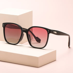 Chic oversized black sunglasses with gradient pink lenses and decorative side accents.