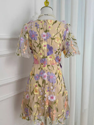 Sheer mesh dress with floral embroidery in purple, yellow, and pink on a nude base, short sleeves.