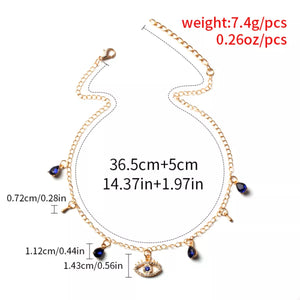 Gold evil eye charm necklace with blue teardrop gems and key charms.