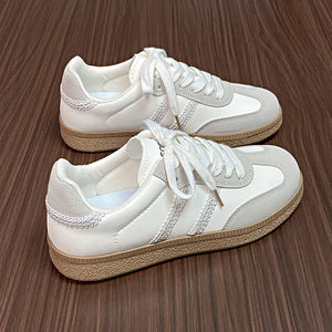 Beige lace-up trainers with retro paneling and decorative stitching detail.