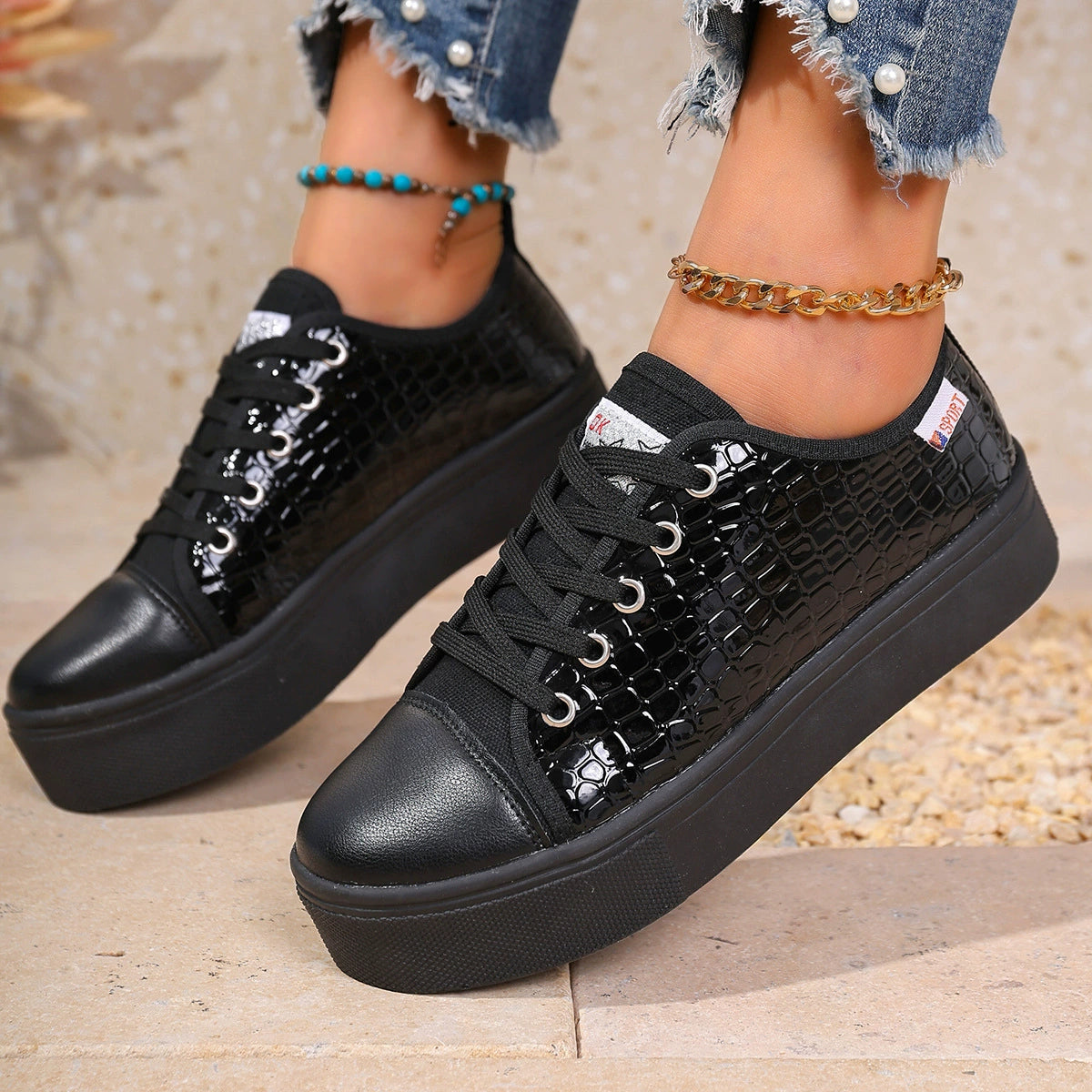 Black crocodile embossed platform sneakers with chunky soles and lace-up closure.