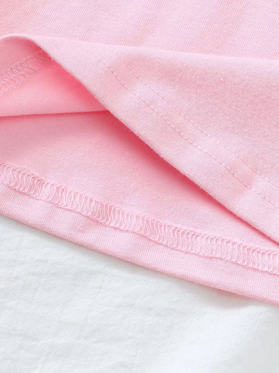 Pink cotton polo shirt hem detail with strawberry embroidery visible.