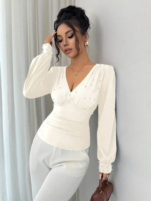 Pearl ruched V-neck blouse in beige with long sleeves and pearl embellishments.