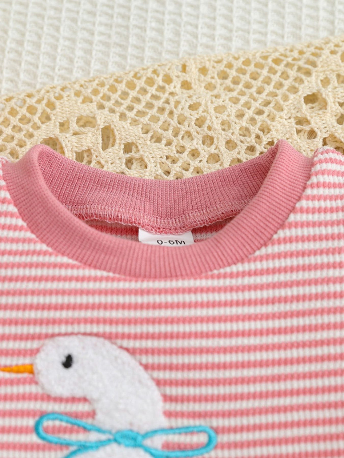 Pink striped baby set with embroidered duck and blue bow detail.