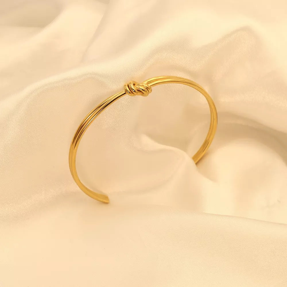 bracelet in gold featuring knot detail and open cuff fit