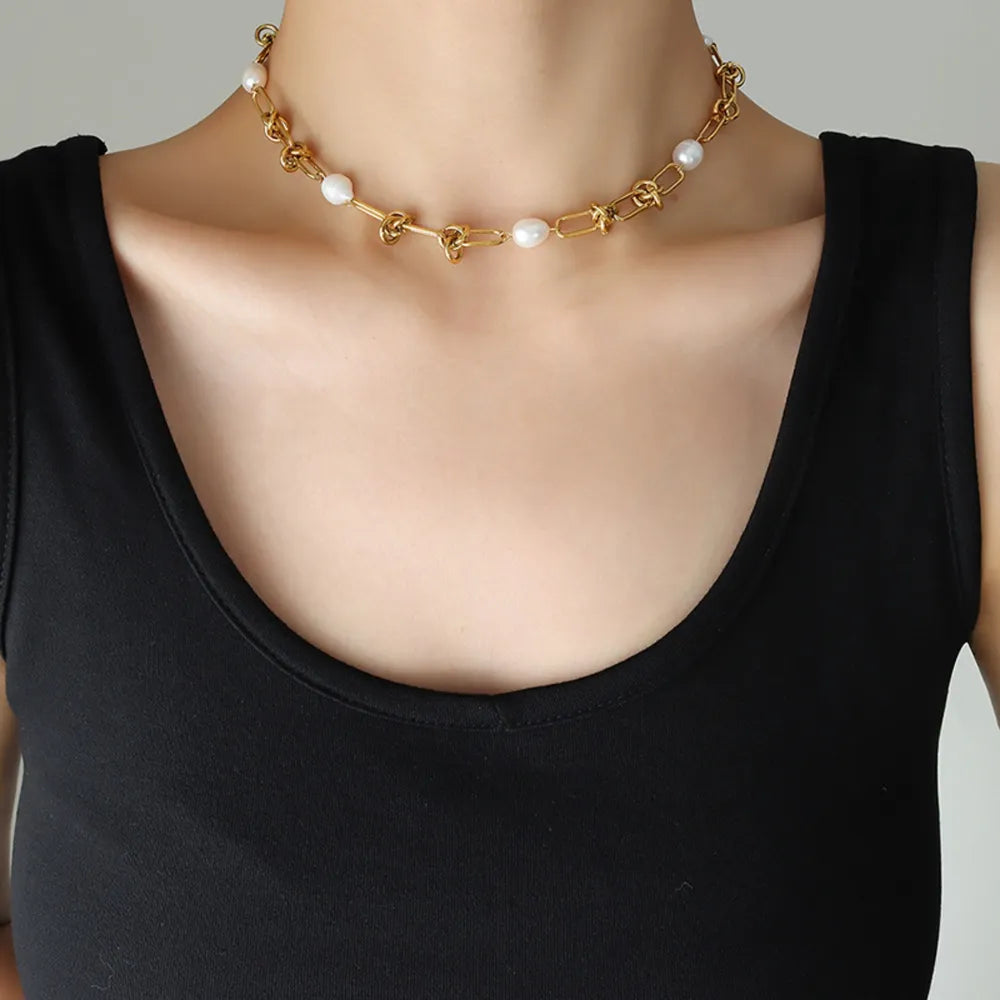 Gold linked pearl knot collar necklace with chain and pearl accents.