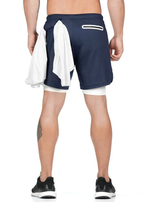 Navy layered performance shorts with white built-in compression shorts and a white towel draped over the side.