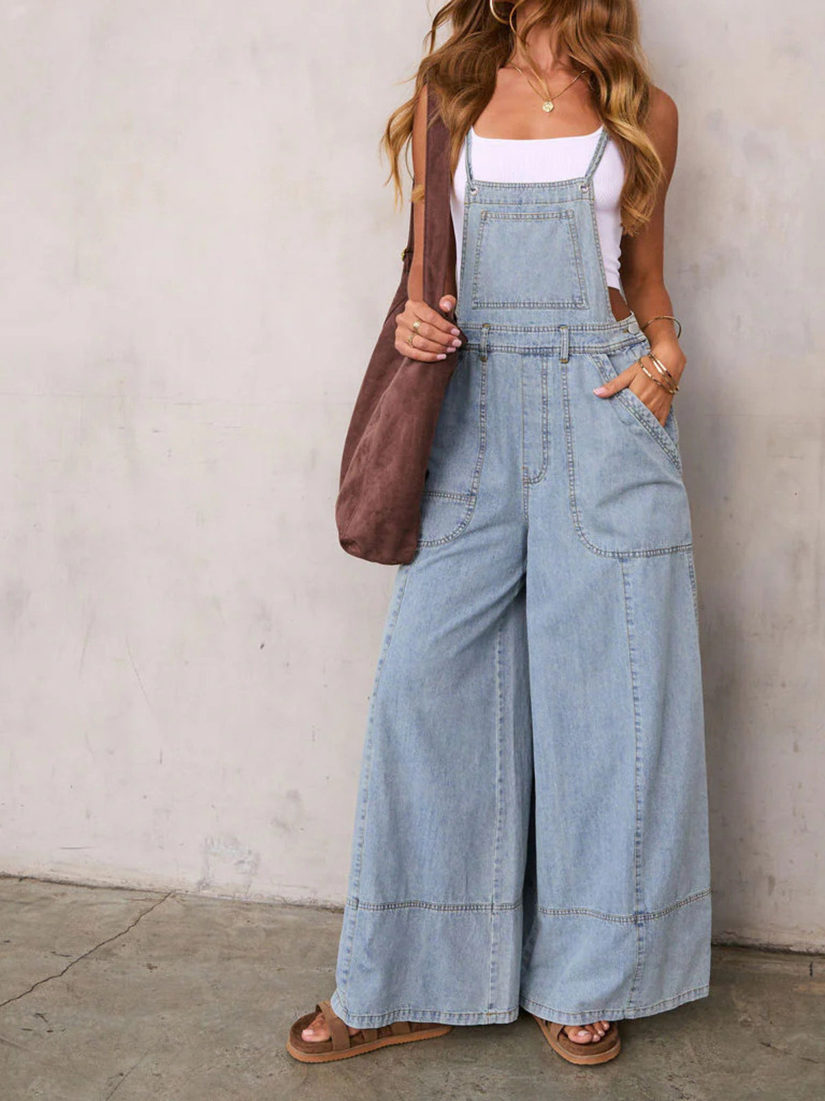 Light wash denim overalls with wide legs, adjustable straps, and front pockets.