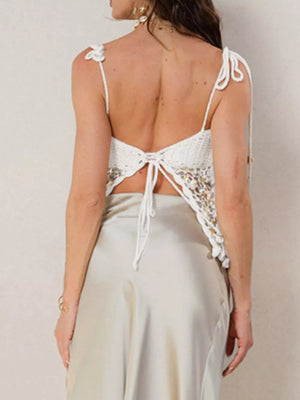 White crochet crop top with sequin details and tie back, styled with a satin skirt.