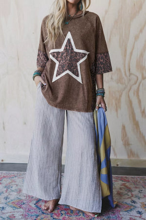 Brown graphic tee with leopard print star and cheetah print sleeves, paired with grey striped wide-leg pants.