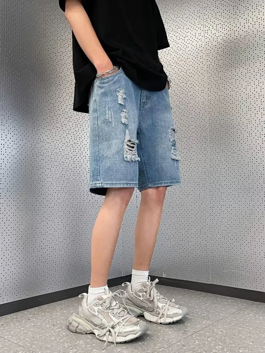 Men's light wash distressed denim shorts with wide leg and raw hem.