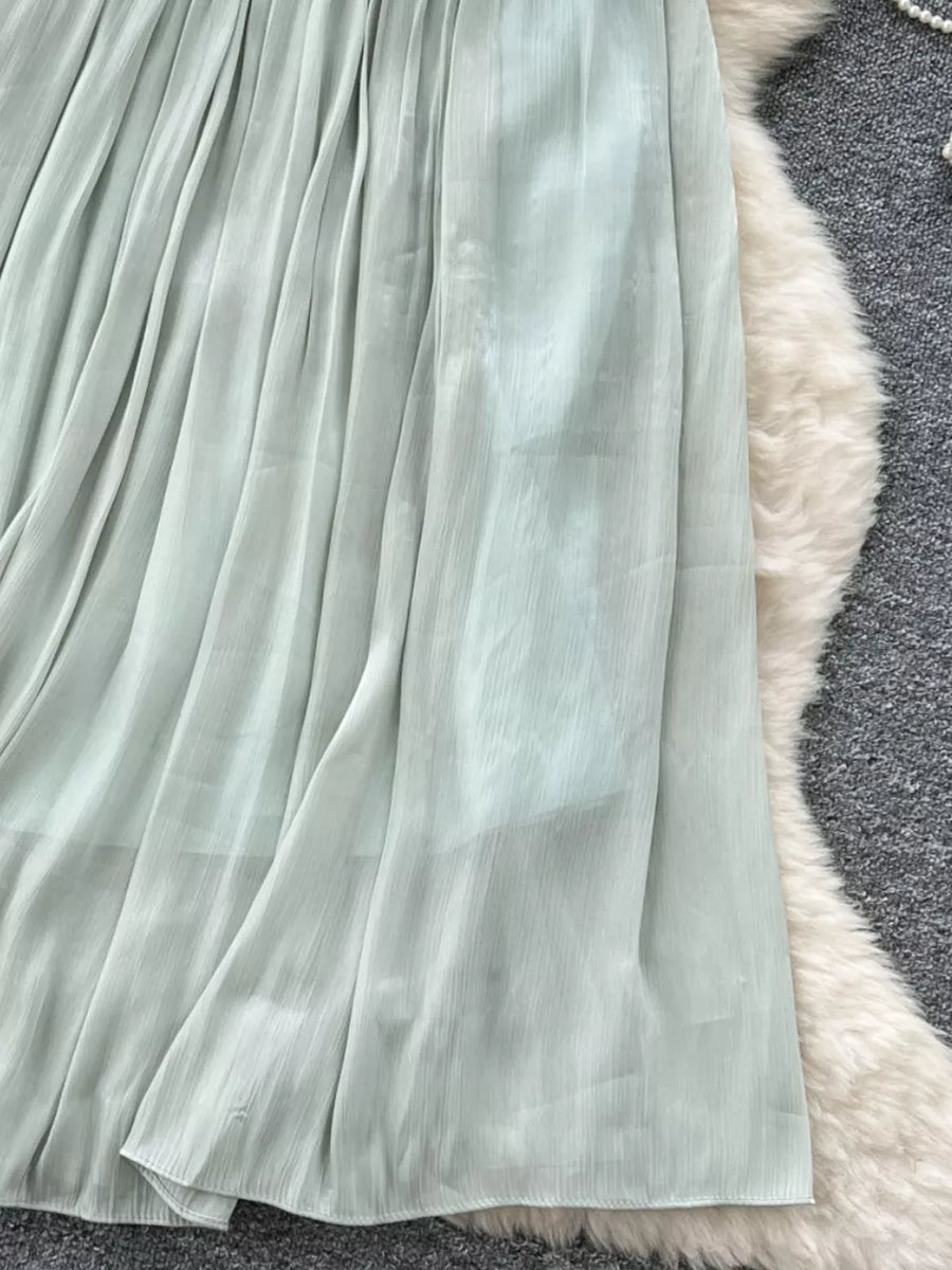 Light green pleated maxi skirt with a flowy, sheer fabric.