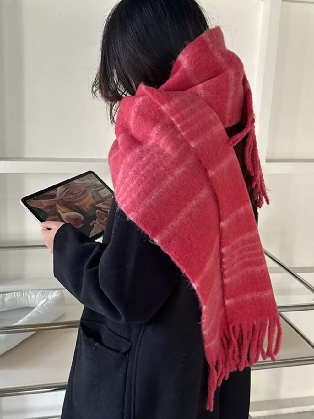 Pink striped scarf with fringe hem and soft texture.