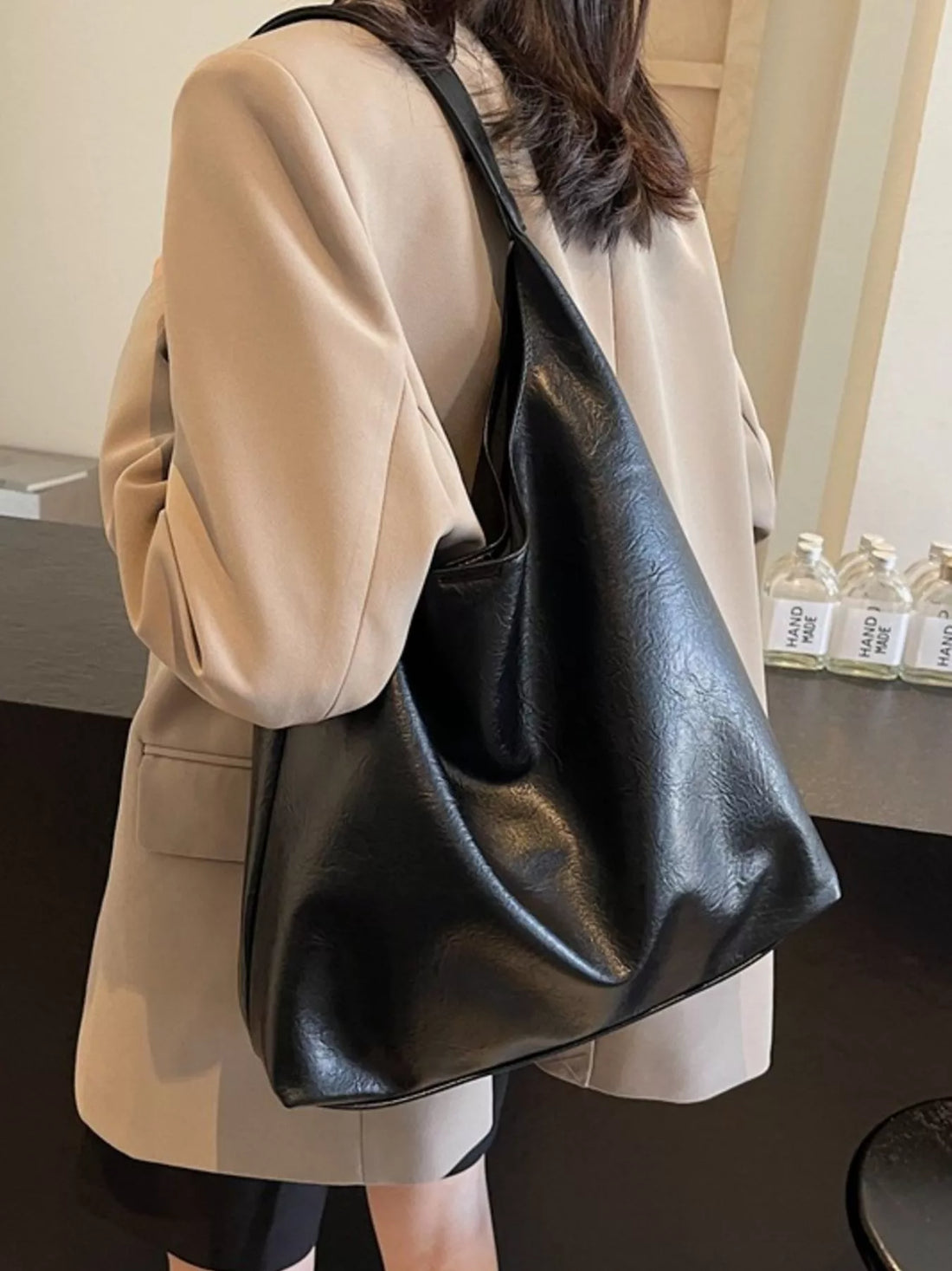 Black sculptural PU leather tote bag with slouchy silhouette and single strap.