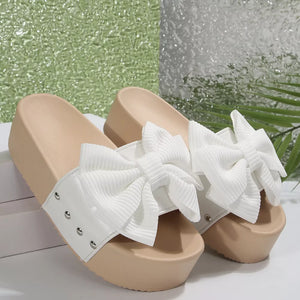 White ribbed bow platform sandals with stud accents and tan soles.