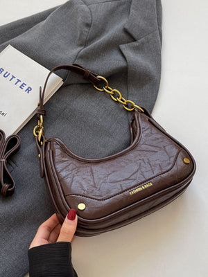 Coffee color crescent shoulder bag with chunky gold chain accent and ruched texture.