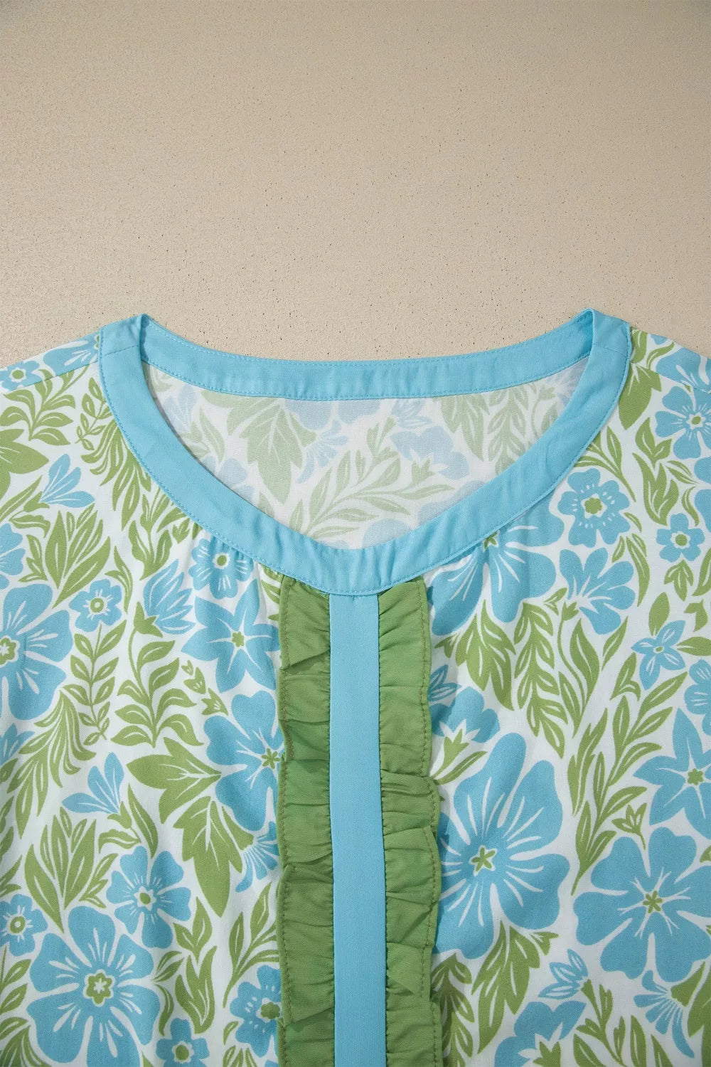 Floral ruffled maternity blouse with blue trim and green ruffles.