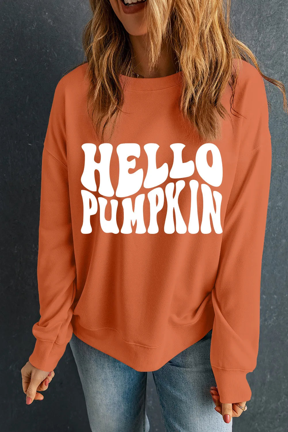 Orange crew neck long sleeve sweater with white "HELLO PUMPKIN" graphic print