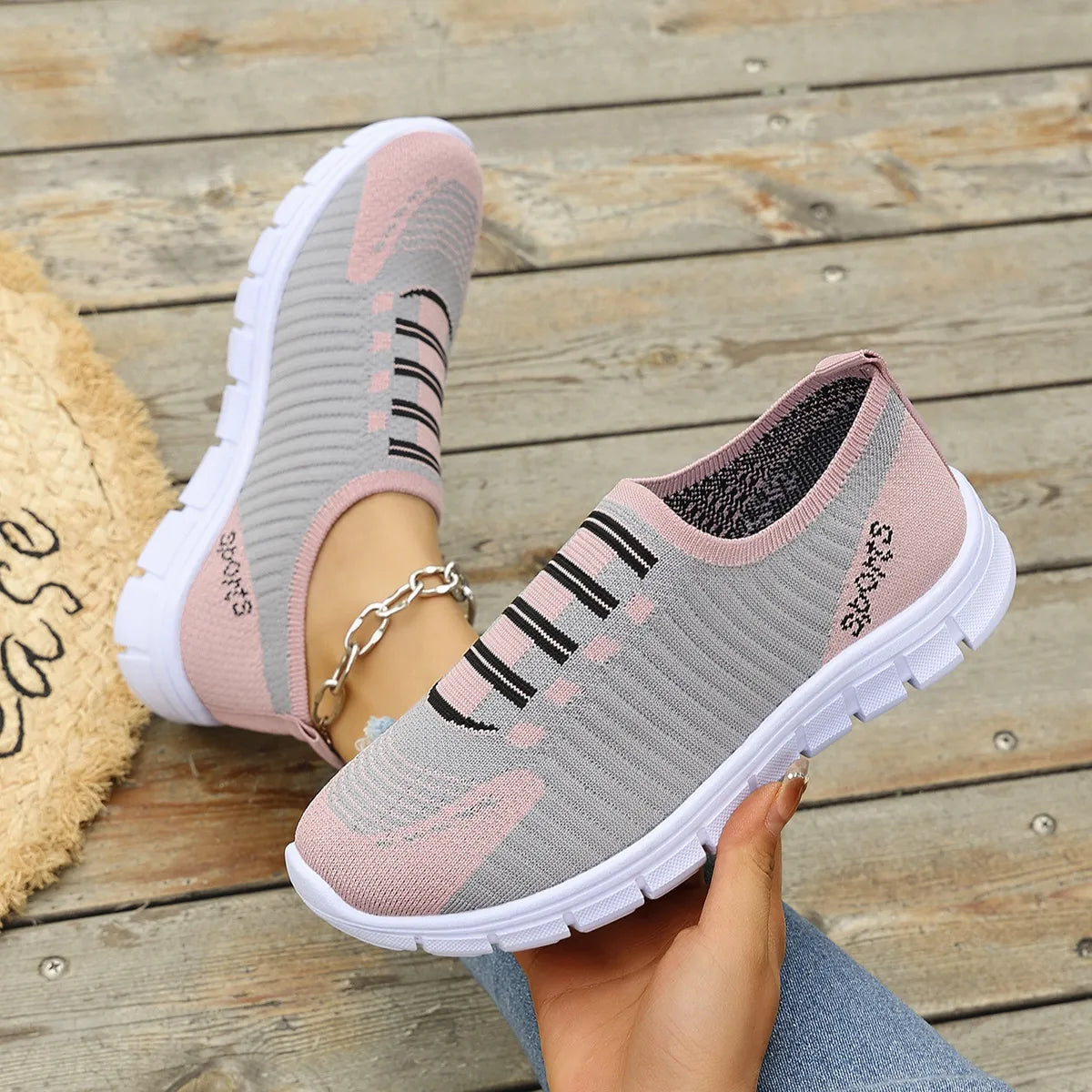 Ribbed knit slip-on sneakers in gray and dusty pink with black stripe detail and white soles.