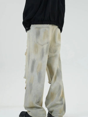 Distressed wide-leg jeans in Yellow Mud with a tie-dye effect and ripped details.