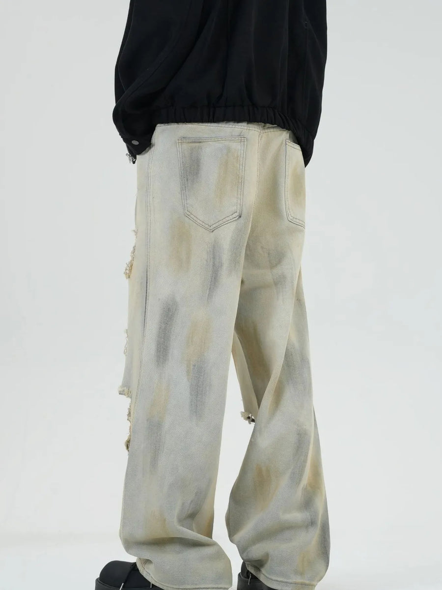 Distressed wide-leg jeans in Yellow Mud with a tie-dye effect and ripped details.