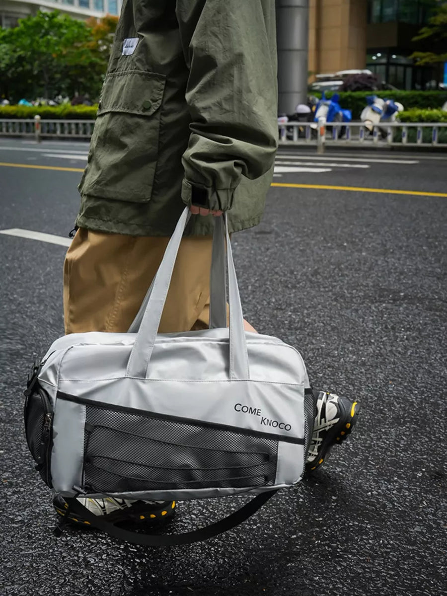 Sleek grey duffel bag with mesh pockets and adjustable strap, perfect for gym.