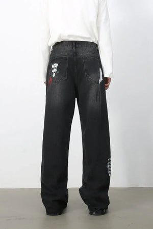 Dark wide-leg jeans with painterly brushstroke details and distressed accents.