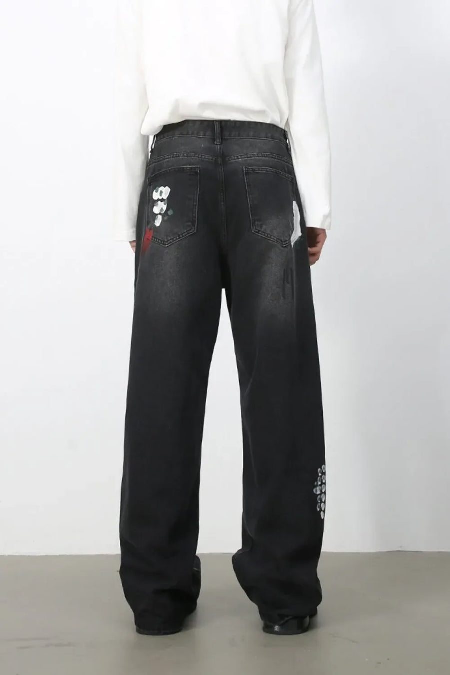 Dark wide-leg jeans with painterly brushstroke details and distressed accents.