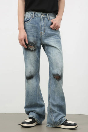 Distressed flare leg denim jeans in medium wash cotton with ripped details.