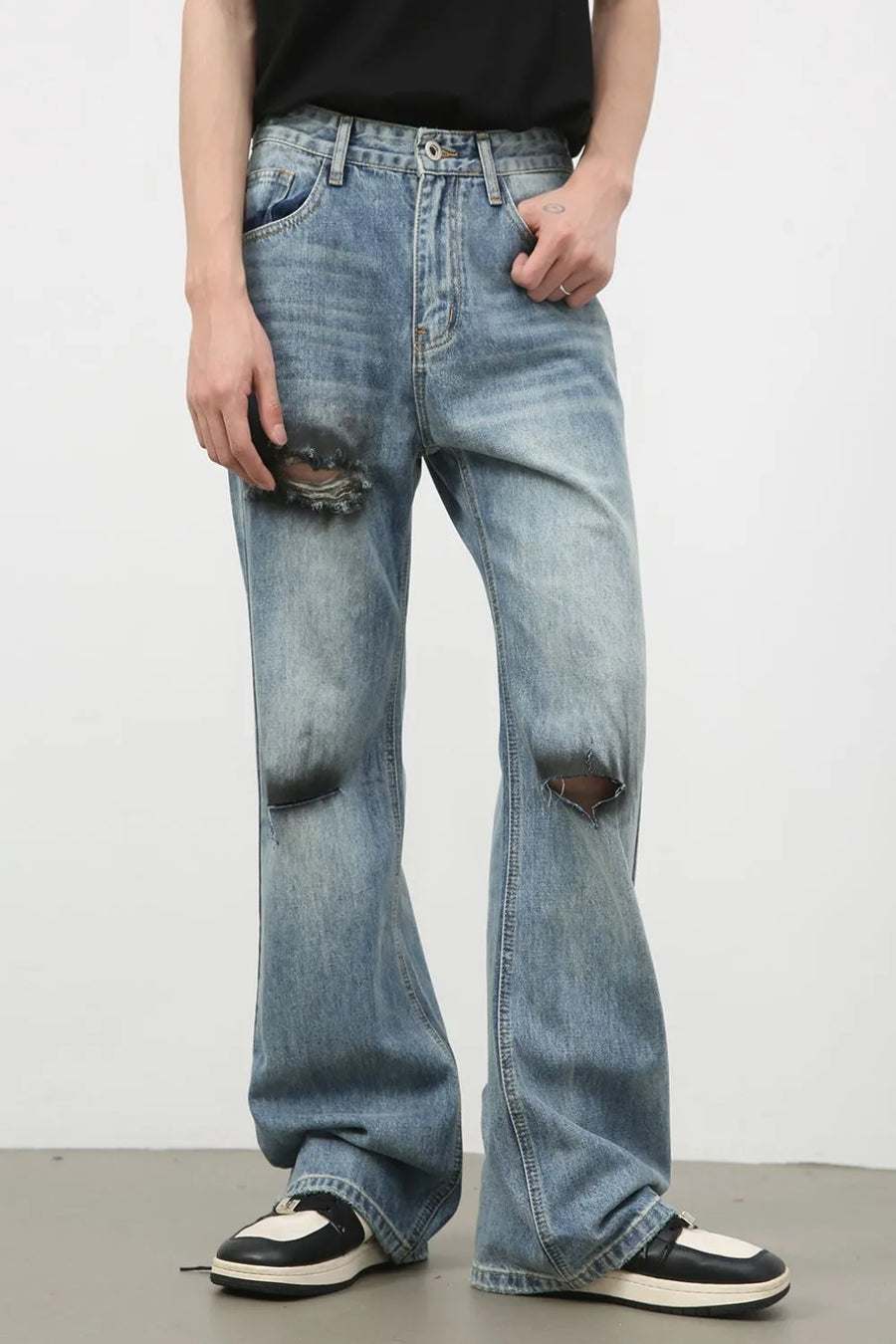 Distressed flare leg denim jeans in medium wash cotton with ripped details.