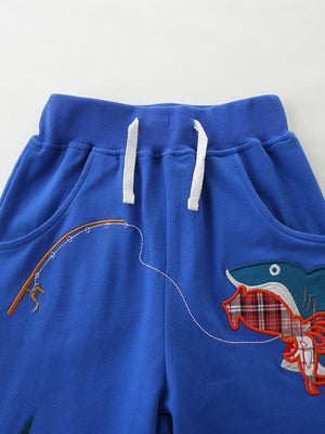 Blue cotton toddler shorts with shark fishing graphic and drawstring waist