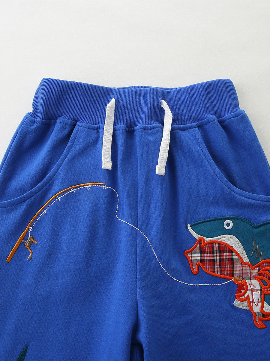 Blue cotton toddler shorts with shark fishing graphic and drawstring waist